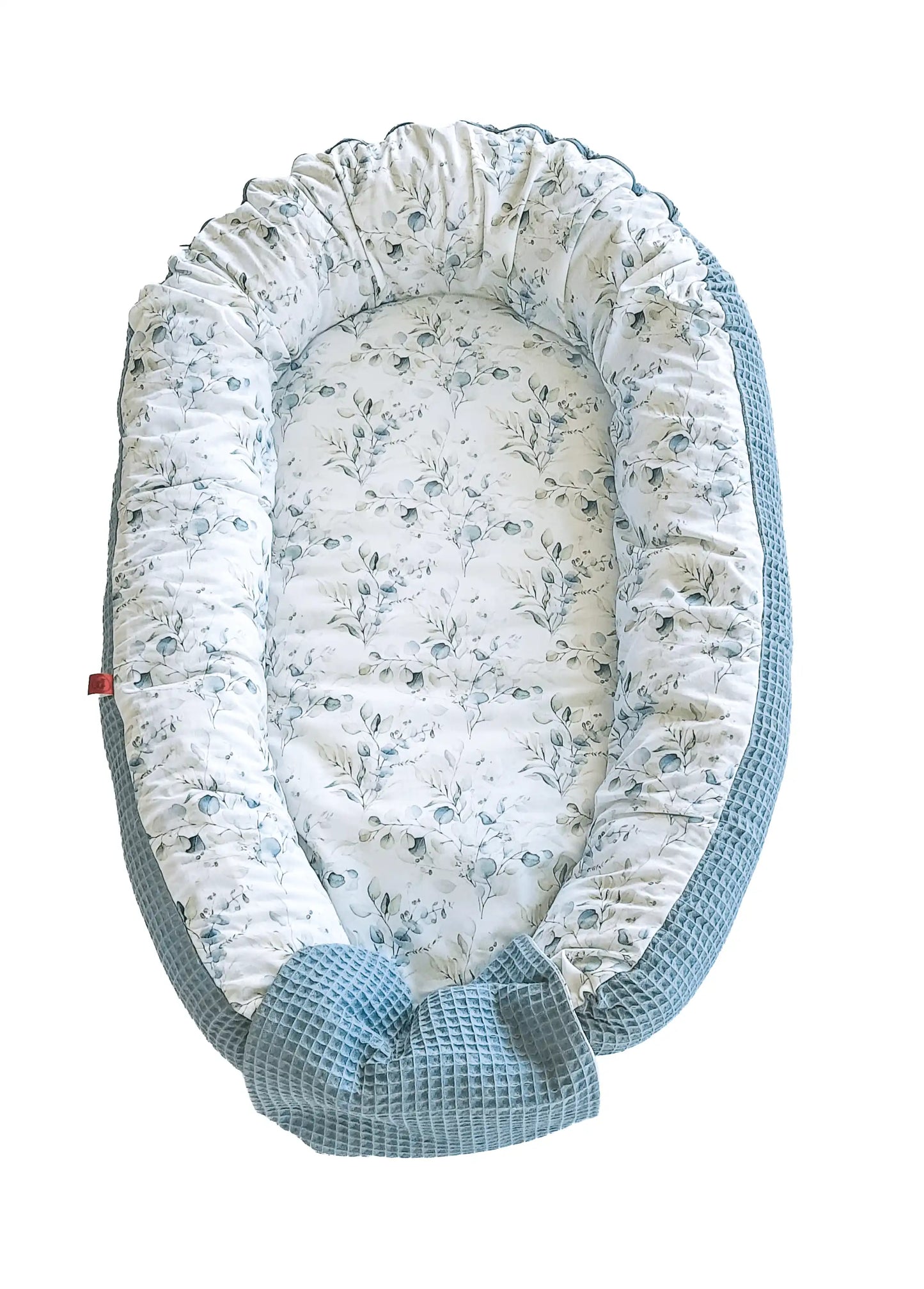 zweifarbiges Babynest: die eine Seite hat ein glattes Eukalypus-Muster und die andere einen grünen Waffelstoff
