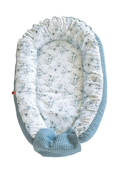 zweifarbiges Babynest: die eine Seite hat ein glattes Eukalypus-Muster und die andere einen grünen Waffelstoff