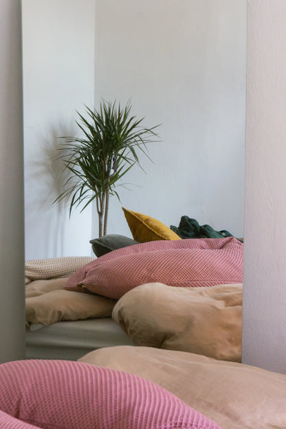 rosafarbenes Stillkissen liegt auf gemütlichem Bett