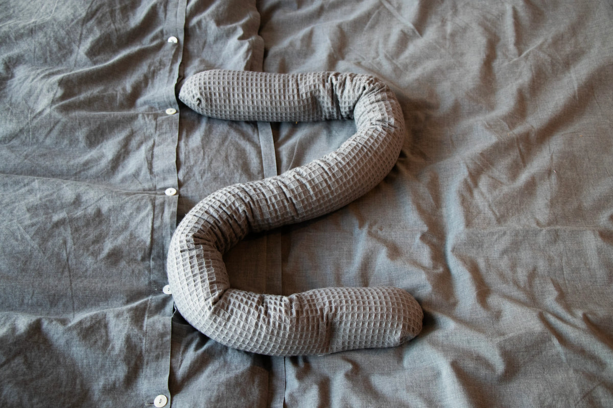 Kreativkopf Kinderwagenschlange mit Waffelbezug in Grau liegt auf einem Bett