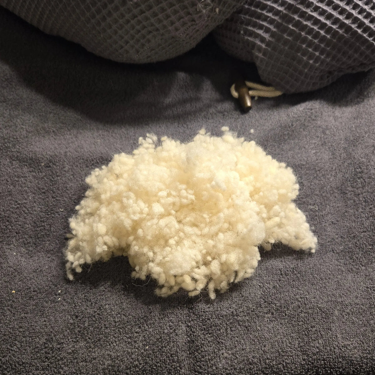 Nahaufnahme der naturbelassenen Schafwollkugeln aus der Füllung des Kreativkopf Stillkissens